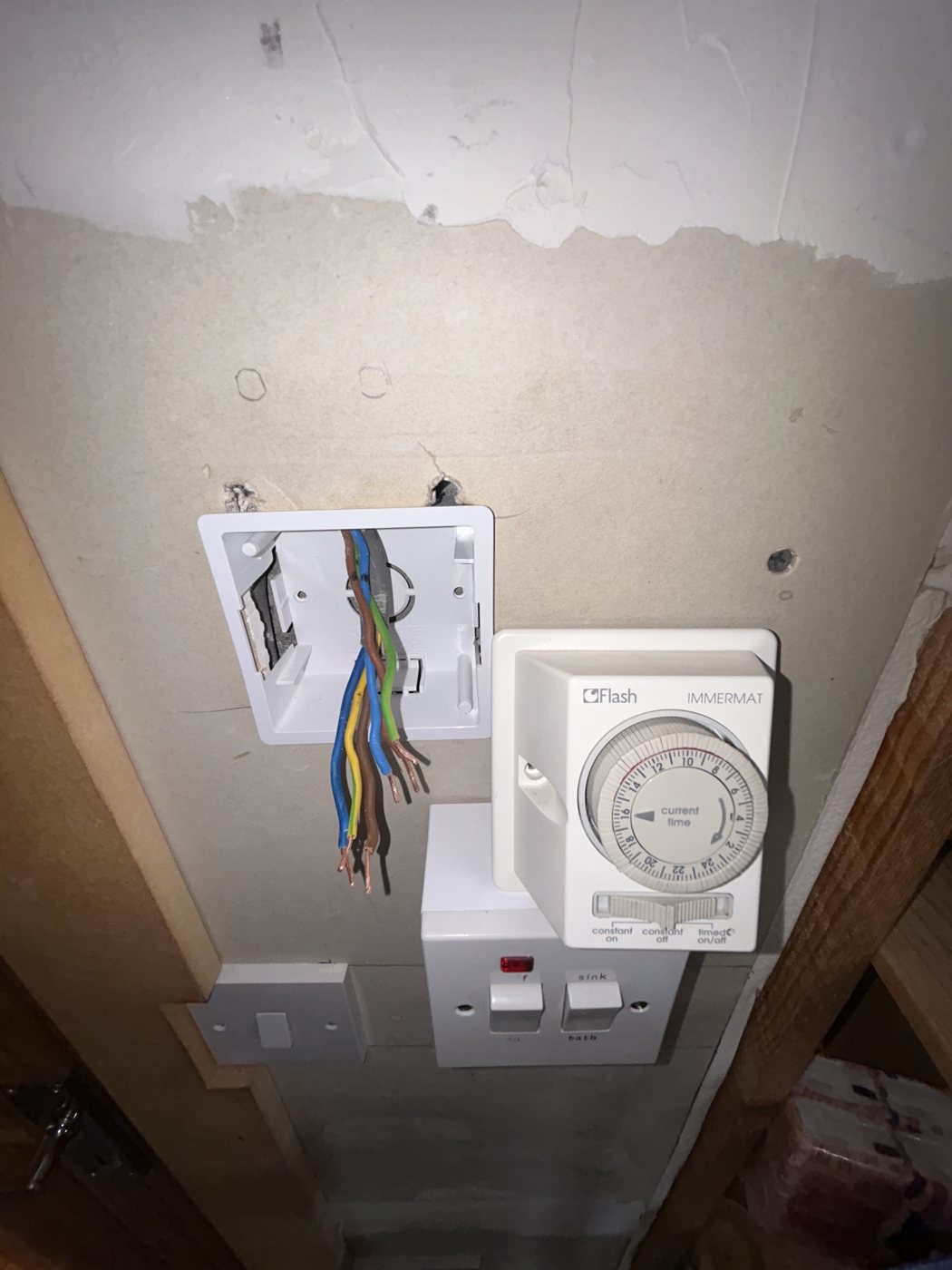 An immersion timer and switch being wired on a wall